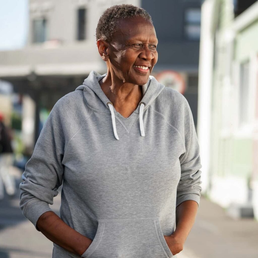 Cancer survivor smiling confidently outdoors after successful treatment at CurePoint Cancer Center.