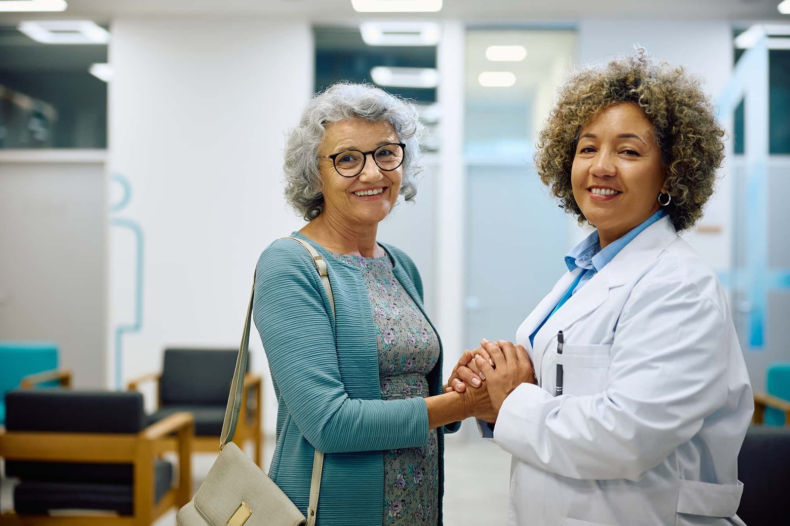 Smiling cancer survivor holding hands with female oncologist at CurePoint Cancer Center